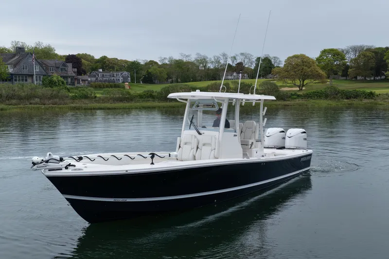 Slide: The Image of 2025 Regulator 30XO boat cruising on a calm lake near a scenic shoreline. - 4