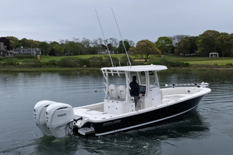 Slide: The Image of 2025 Regulator 30XO boat with dual Yamaha engines on a calm lake. - 11