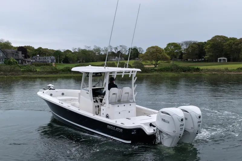 Slide: The Image of 2025 Regulator 30XO boat with dual Yamaha engines cruising on a calm lake. - 8