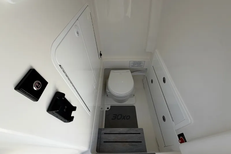 Slide: The Image of 2025 Regulator 30XO boat interior with compact marine toilet and storage compartments. - 59