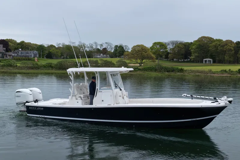 Slide: The Image of 2025 Regulator 30XO boat on calm water, showcasing sleek design and twin engines. - 1