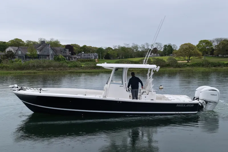 Slide: The Image of 2025 Regulator 30XO boat on calm water near a scenic shoreline. - 6