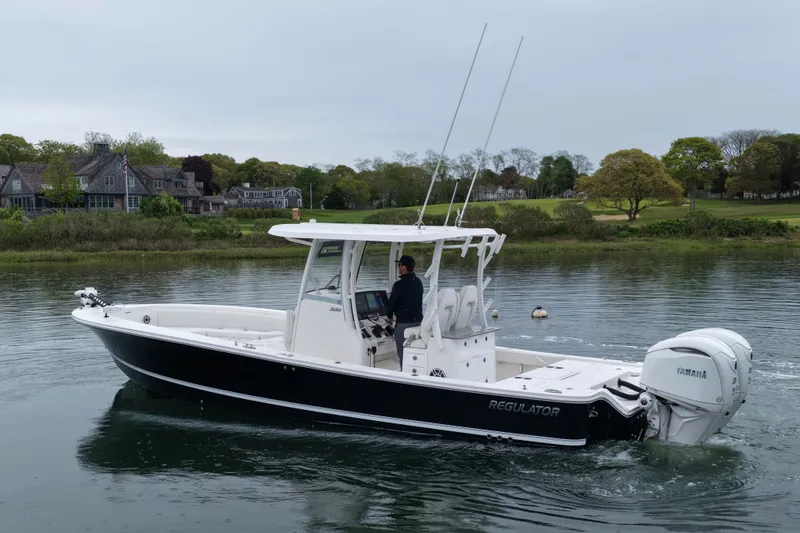 Slide: The Image of 2025 Regulator 30XO boat cruising on a calm lake near waterfront homes. - 7