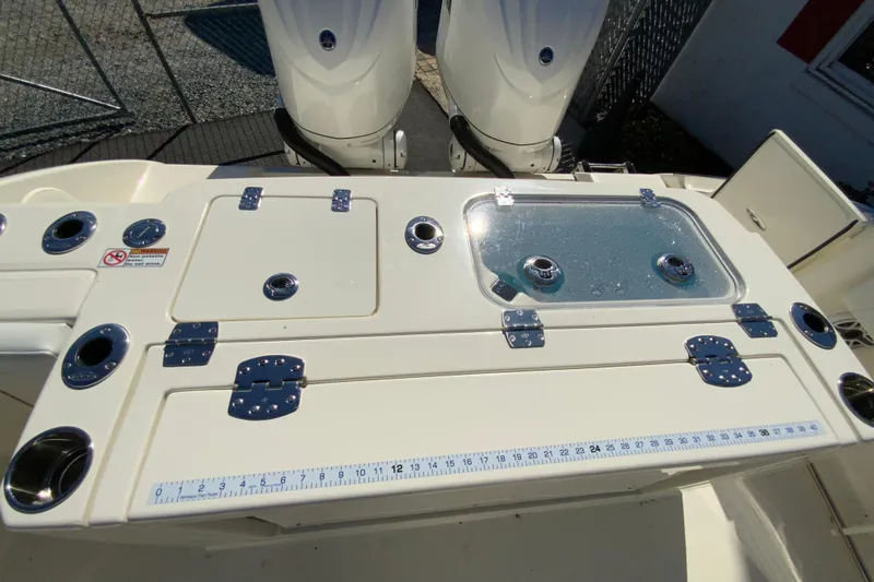 Slide: The Image of 2025 Cobia 285 Open Center Console fishing station with rod holders and measuring ruler. - 16