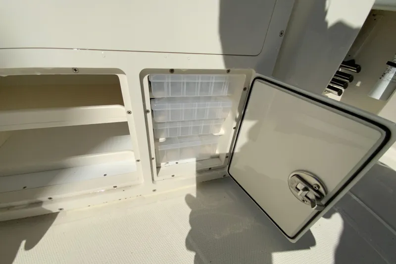 Slide: The Image of 2025 Cobia 285 Open Center Console storage compartment with open door and organized shelves. - 24