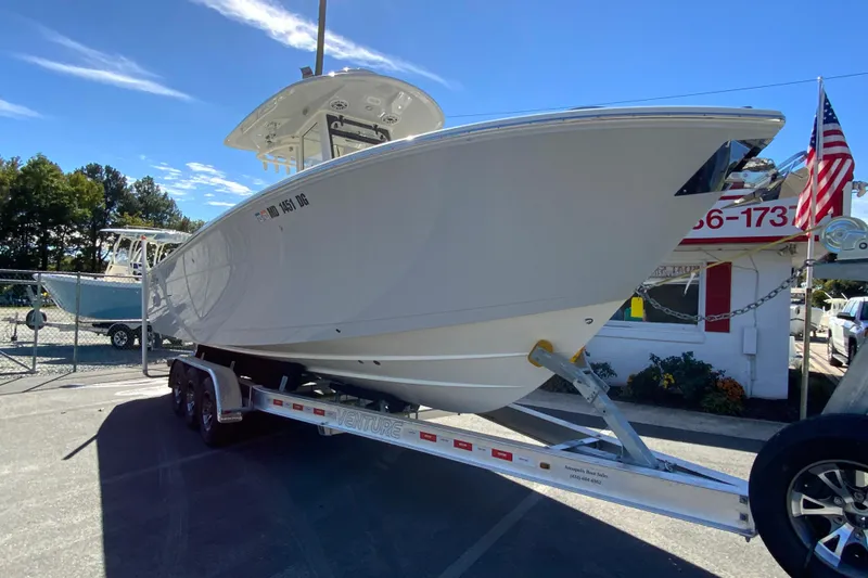 Slide: The Image of 2025 Cobia 285 Open Center Console boat on trailer, displayed outdoors. - 3