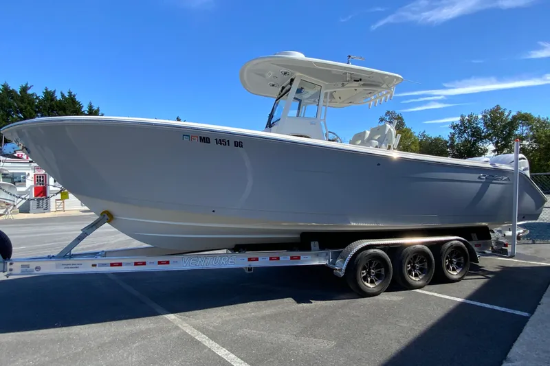 Slide: The Image of 2025 Cobia 285 Open Center Console boat on a trailer, parked outdoors. - 6