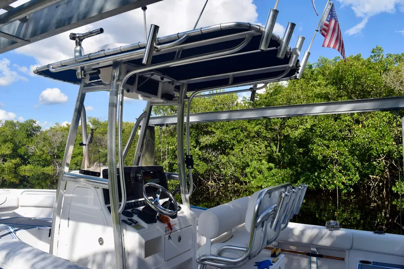 Slide: The Image of 2018 Sea Hunt Ultra 211 boat with T-top, steering wheel, and American flag in scenic setting. - 13