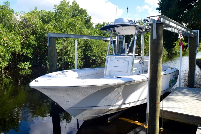 Slide: The Image of 2018 Sea Hunt Ultra 211 boat docked near lush greenery. - 2
