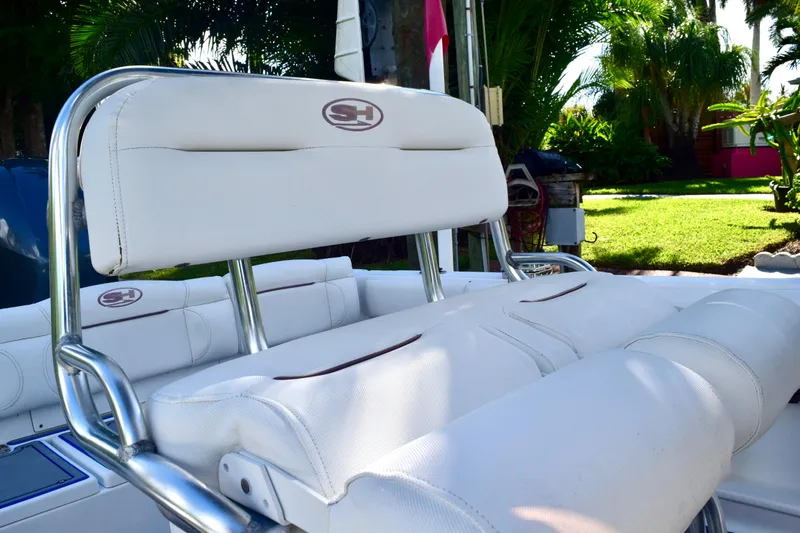 Slide: The Image of White seating on 2018 Sea Hunt Ultra 211 boat, surrounded by lush greenery. - 31