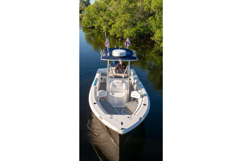Slide: The Image of 2018 Sea Hunt Ultra 211 boat on calm water, featuring flags and a center console. - 44