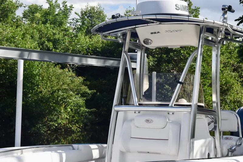 Slide: The Image of 2018 Sea Hunt Ultra 211 boat with T-top, surrounded by lush greenery. - 5