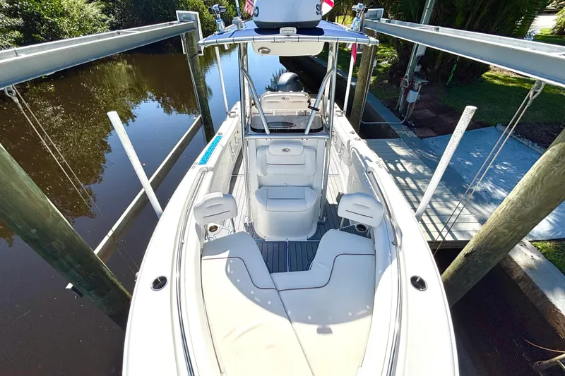 Slide: The Image of 2018 Sea Hunt Ultra 211 boat docked on a calm waterway, showcasing sleek design and seating. - 64