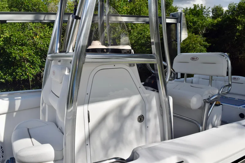 Slide: The Image of 2018 Sea Hunt Ultra 211 boat interior with seating and console, surrounded by greenery. - 7