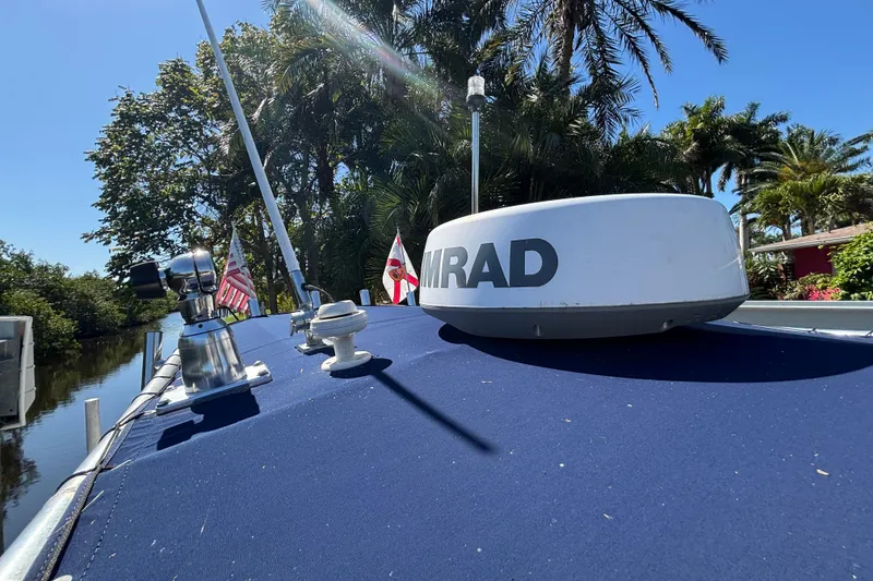 Slide: The Image of 2018 Sea Hunt Ultra 211 boat with radar, flags, and lush tropical background. - 75