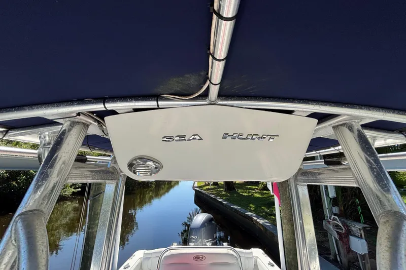 Slide: The Image of 2018 Sea Hunt Ultra 211 boat with canopy, docked on a calm waterway. - 78