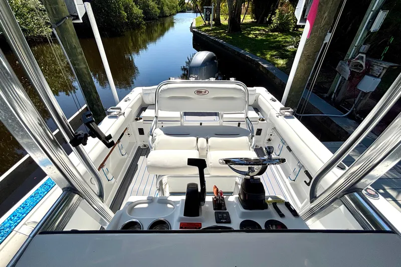 Slide: The Image of 2018 Sea Hunt Ultra 211 boat interior with steering wheel and seating, docked by a canal. - 79