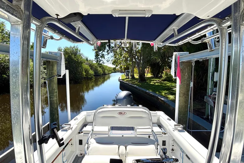 Slide: The Image of 2018 Sea Hunt Ultra 211 boat on a serene river, surrounded by lush greenery. - 80