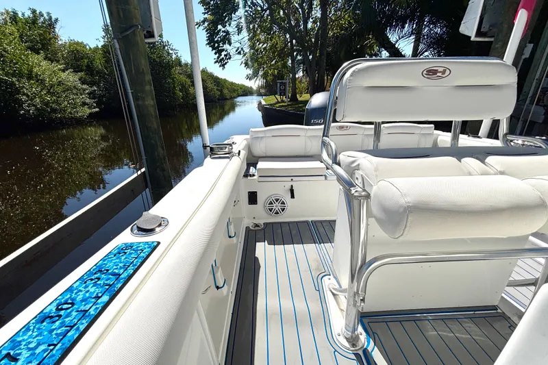 Slide: The Image of 2018 Sea Hunt Ultra 211 boat interior with seating, docked by a scenic waterway. - 83