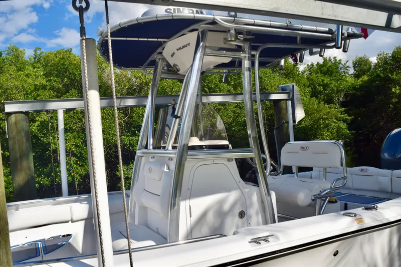 Slide: The Image of 2018 Sea Hunt Ultra 211 boat with T-top, docked near lush greenery. - 9