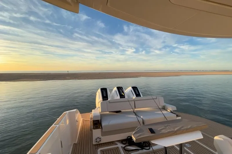 Slide: The Image of 2024 Tiara Yachts 48 LS cruising on a calm, scenic waterway under a partly cloudy sky. - 2