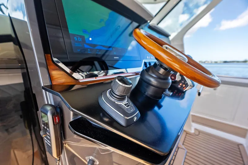 Slide: The Image of 2024 Tiara Yachts 48 LS helm with wooden steering wheel and navigation display. - 37