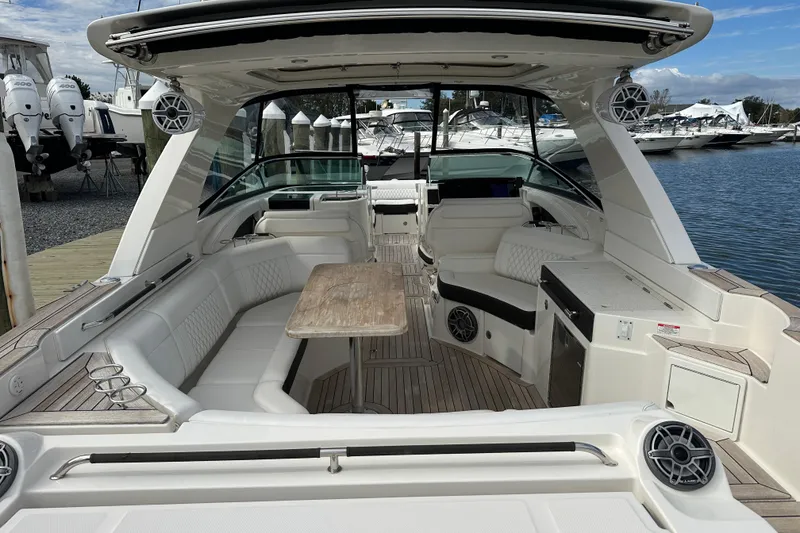 Slide: The Image of 2019 Sea Ray SLX 350 Outboard boat interior with seating, table, and speakers at a marina. - 11