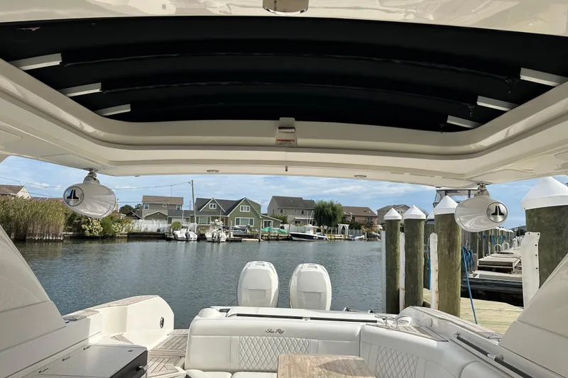 Slide: The Image of 2019 Sea Ray SLX 350 Outboard boat interior with waterfront view and docked houses. - 16