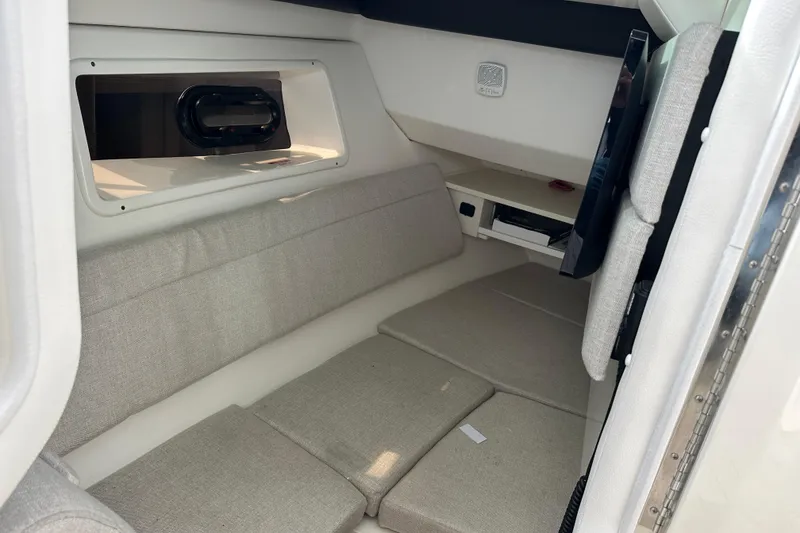Slide: The Image of 2019 Sea Ray SLX 350 Outboard cabin interior with beige seating and window. - 33