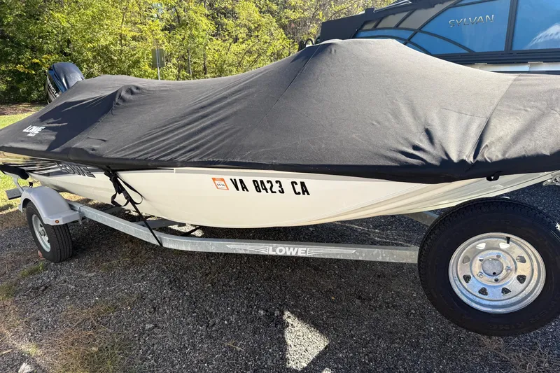 Slide: The Image of 2018 Lowe Stinger 175C boat on trailer with black cover, parked outdoors. - 7
