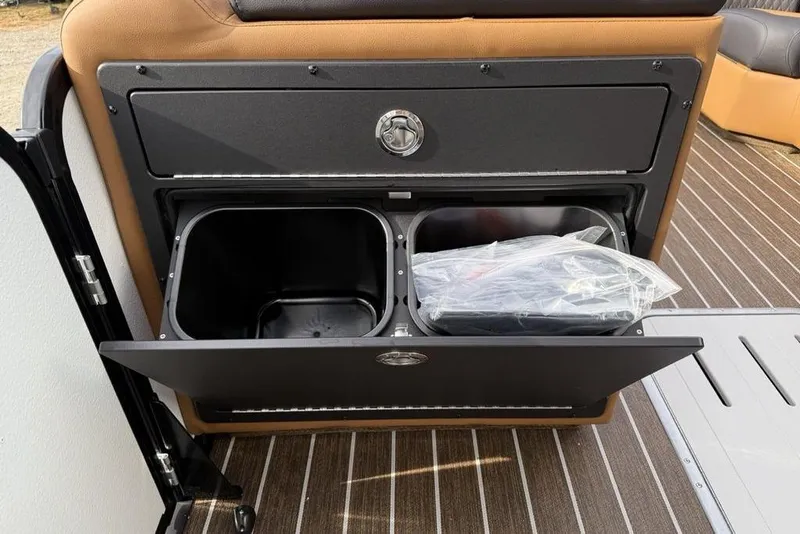 Slide: The Image of Storage compartment on 2026 Premier 230 Sunsation boat with trash bins and brown seating. - 16