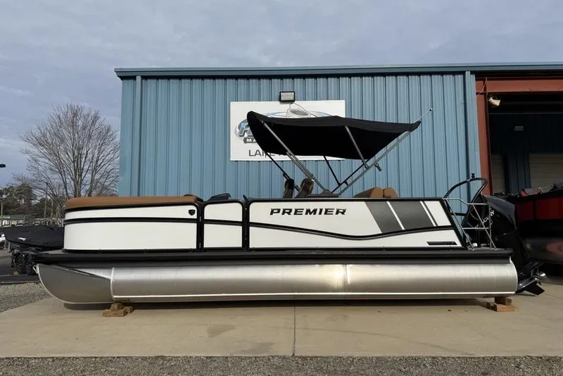 The Image of 2026 Premier 230 Sunsation pontoon boat with canopy, parked outside a blue building. - 3