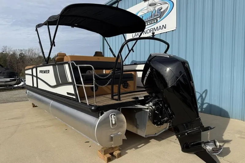Slide: The Image of 2026 Premier 230 Sunsation pontoon boat with Mercury outboard motor, docked near blue building. - 6