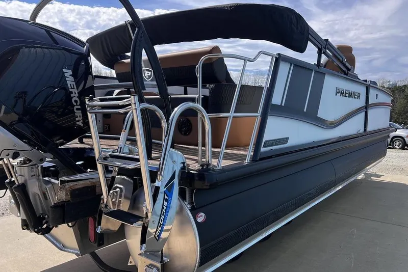 Slide: The Image of 2026 Premier 230 Solaris pontoon boat with Mercury engine, docked under a cloudy sky. - 9