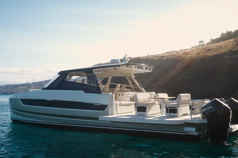 Slide: The Image of 2025 Harris-Kayot 41 boat on serene water with scenic coastal backdrop. - 2