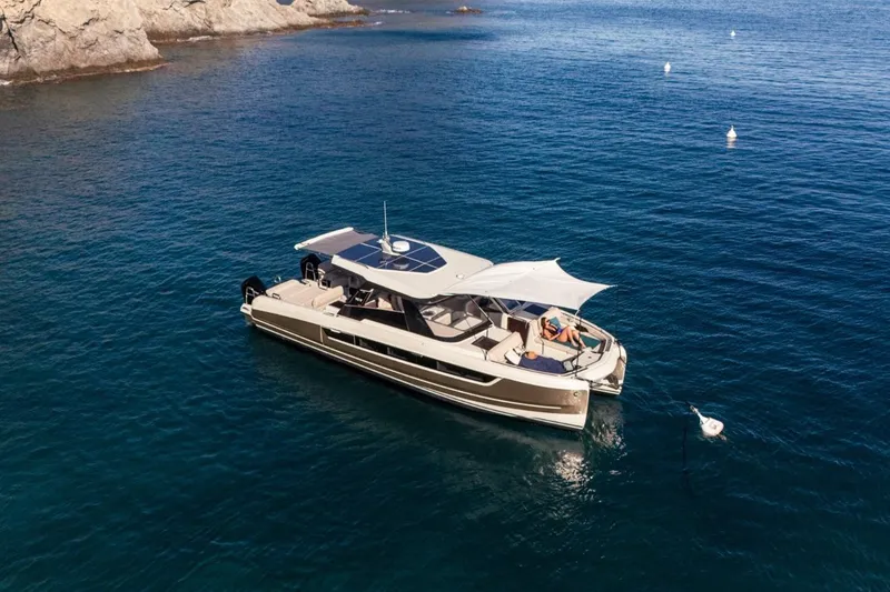 Slide: The Image of 2025 Harris-Kayot 41 yacht anchored in serene blue waters near rocky coastline. - 6