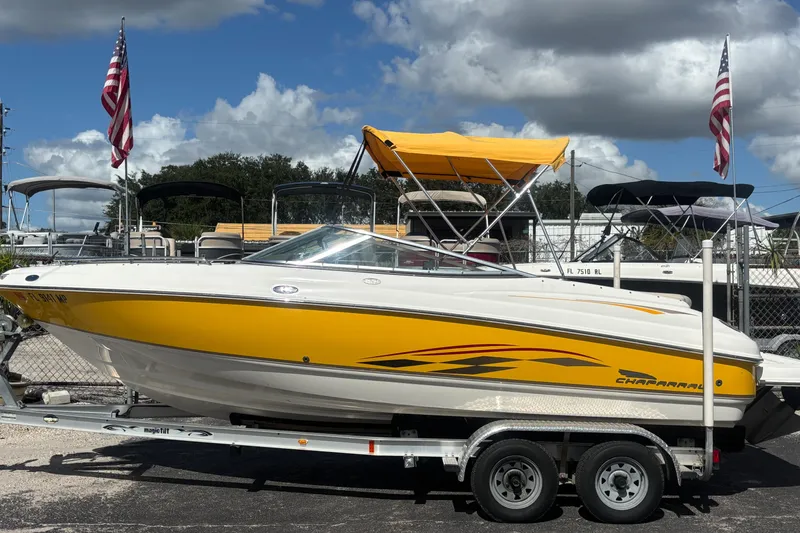 The Image of 2004 Chaparral 210 SSi boat with yellow accents on a trailer, under a blue sky. - 0