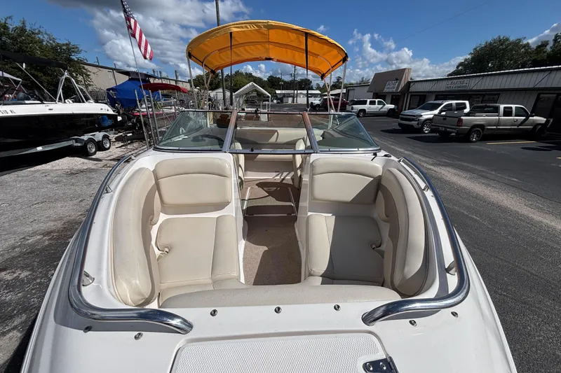 Slide: The Image of 2004 Chaparral 210 SSi boat with yellow canopy, parked outdoors under blue sky. - 10