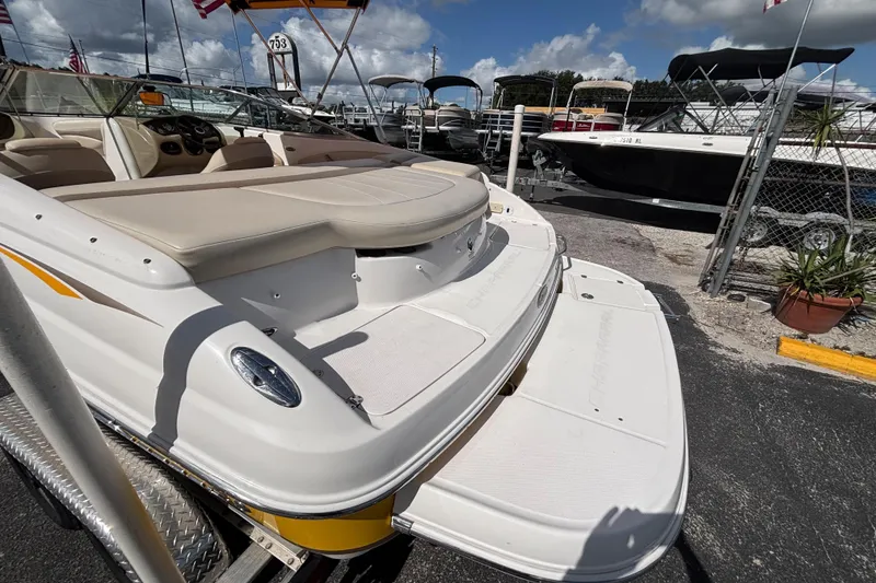 Slide: The Image of 2004 Chaparral 210 SSi boat with beige interior, docked outdoors under a cloudy sky. - 11