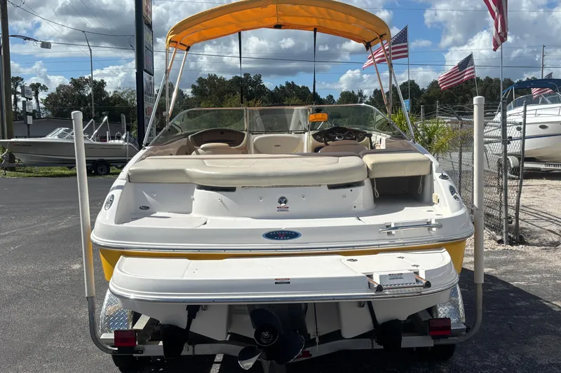 Slide: The Image of 2004 Chaparral 210 SSi boat with yellow canopy, parked outdoors under a blue sky. - 3