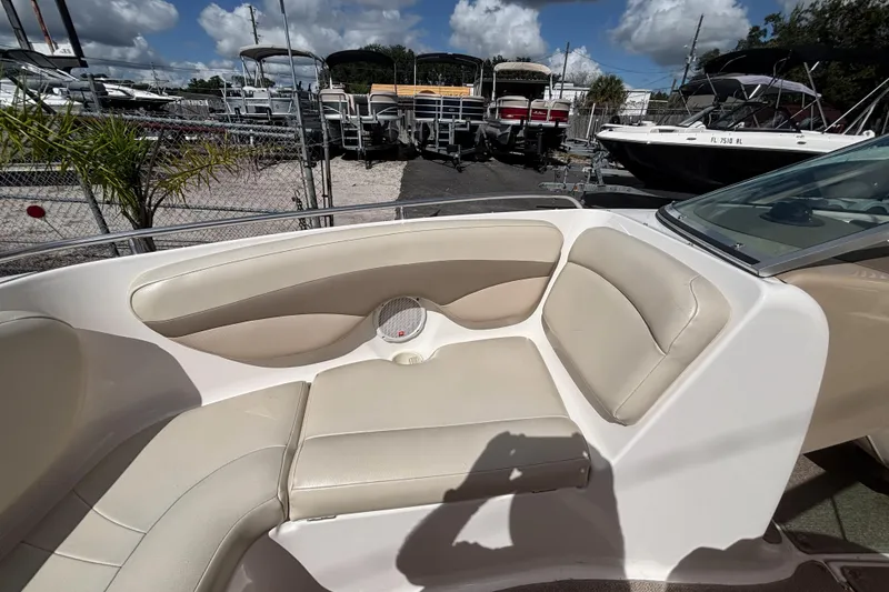 Slide: The Image of 2004 Chaparral 210 SSi boat interior with beige seating, parked in a marina under blue skies. - 38