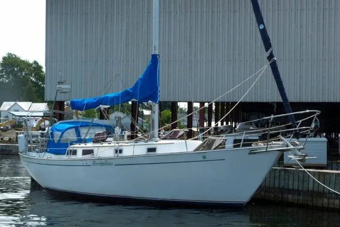 Slide: The Image of 1983 Hinterhoeller Niagara 35 sailboat docked with blue sail cover. - 2