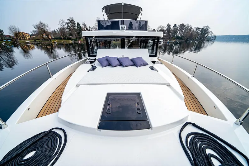 Slide: The Image of 2025 Cobra Sea Master yacht with deck view, cushions, and serene lake backdrop. - 5