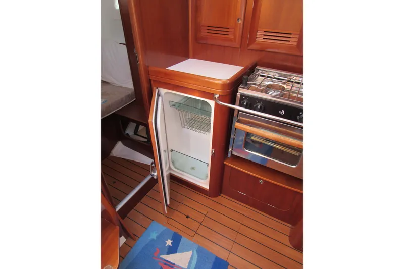 Slide: The Image of 2005 Beneteau Oceanis 373 yacht kitchen with open fridge and stove, wooden interior. - 18