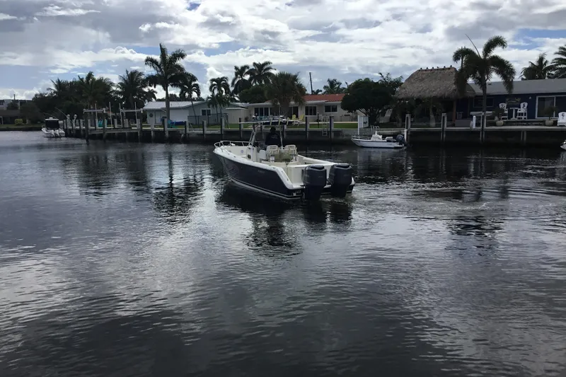 Slide: The Image of 2007 Pursuit C 280 Center Console boat on a calm waterfront with palm trees. - 10