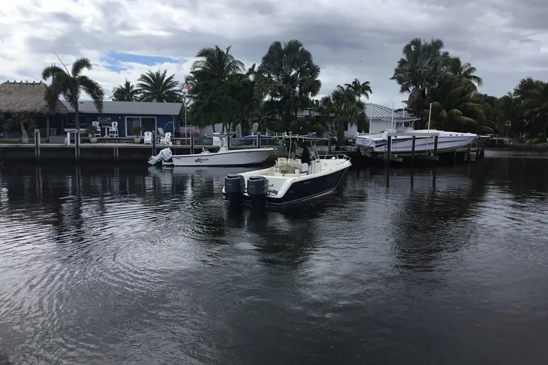 Slide: The Image of 2007 Pursuit C 280 Center Console boat on a calm waterfront with palm trees. - 2
