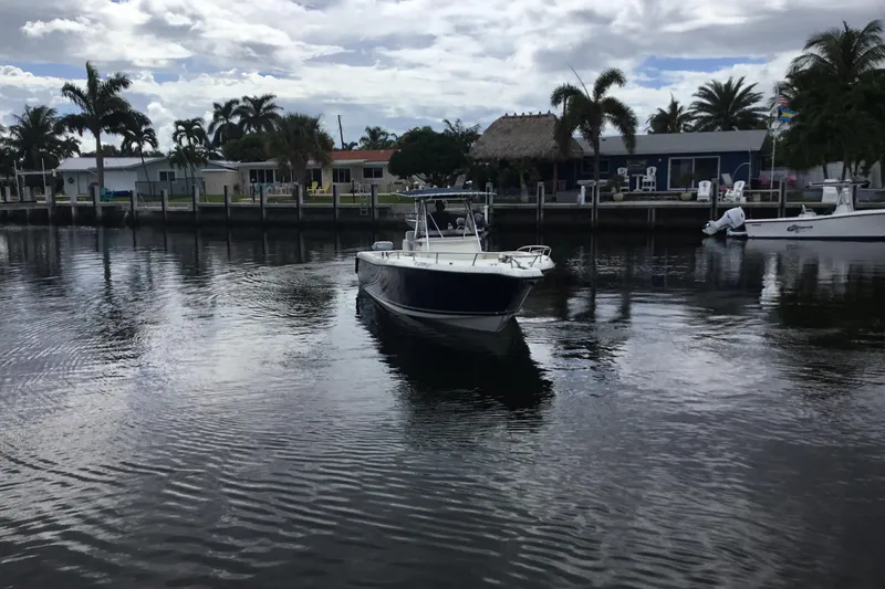 Slide: The Image of 2007 Pursuit C 280 Center Console boat on a calm waterfront with palm trees. - 5
