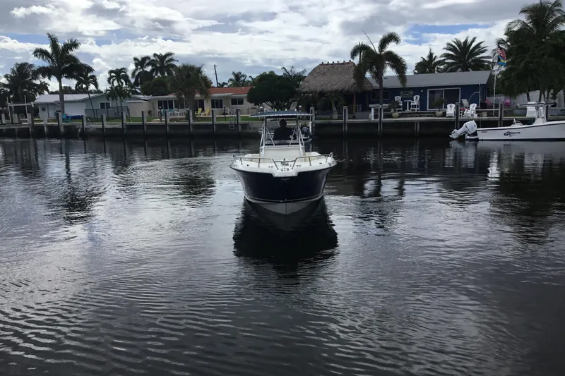 Slide: The Image of 2007 Pursuit C 280 Center Console boat on a calm waterfront with palm trees. - 6