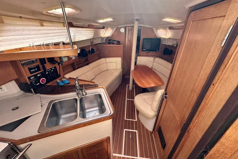 Slide: The Image of Interior of 2008 Catalina 320 sailboat with kitchen, seating area, and wooden finishes. - 35
