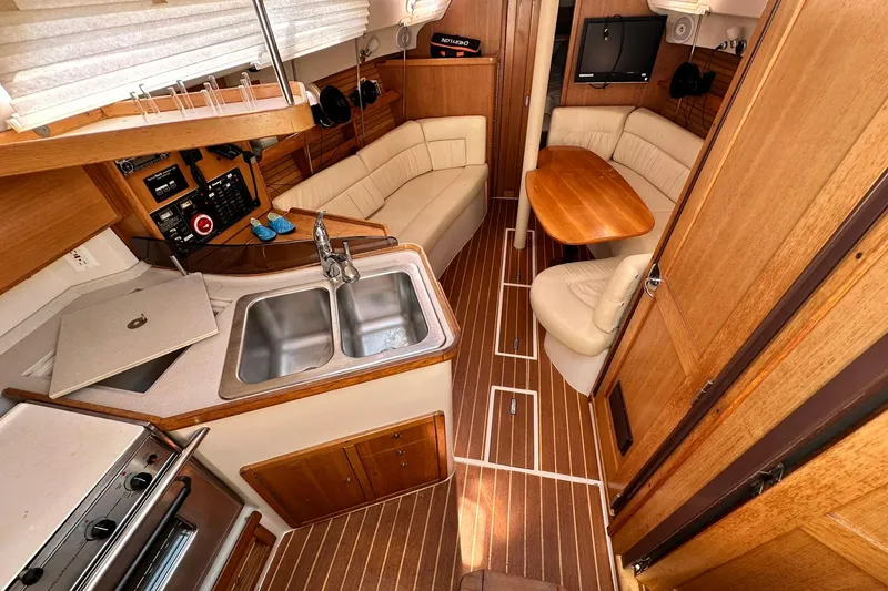 Slide: The Image of Interior of 2008 Catalina 320 sailboat with kitchen, seating, and wooden finishes. - 63